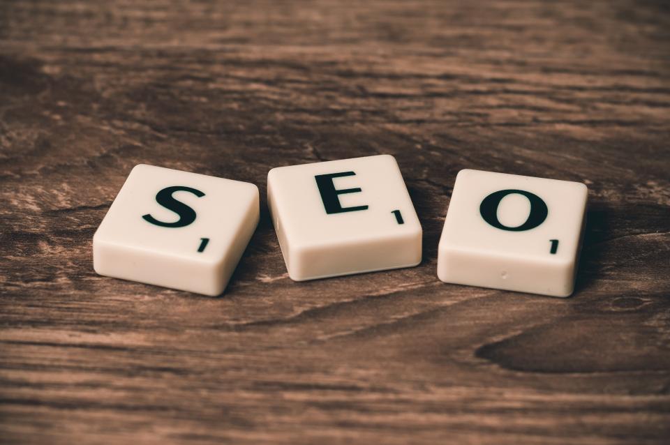 Three Scrabble tiles spelling SEO arranged on a rustic wooden surface