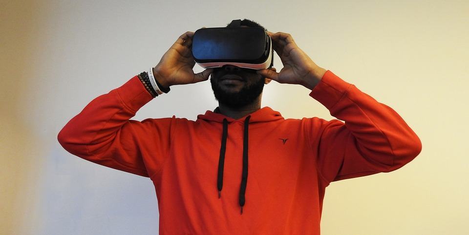 Man in red hoodie putting on a VR headset with both hands
