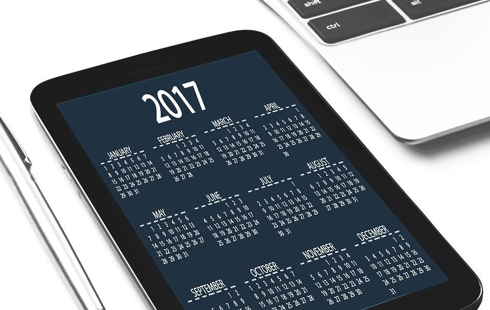 Tablet displaying a 2017 yearly calendar beside a laptop keyboard, representing content planning and scheduling