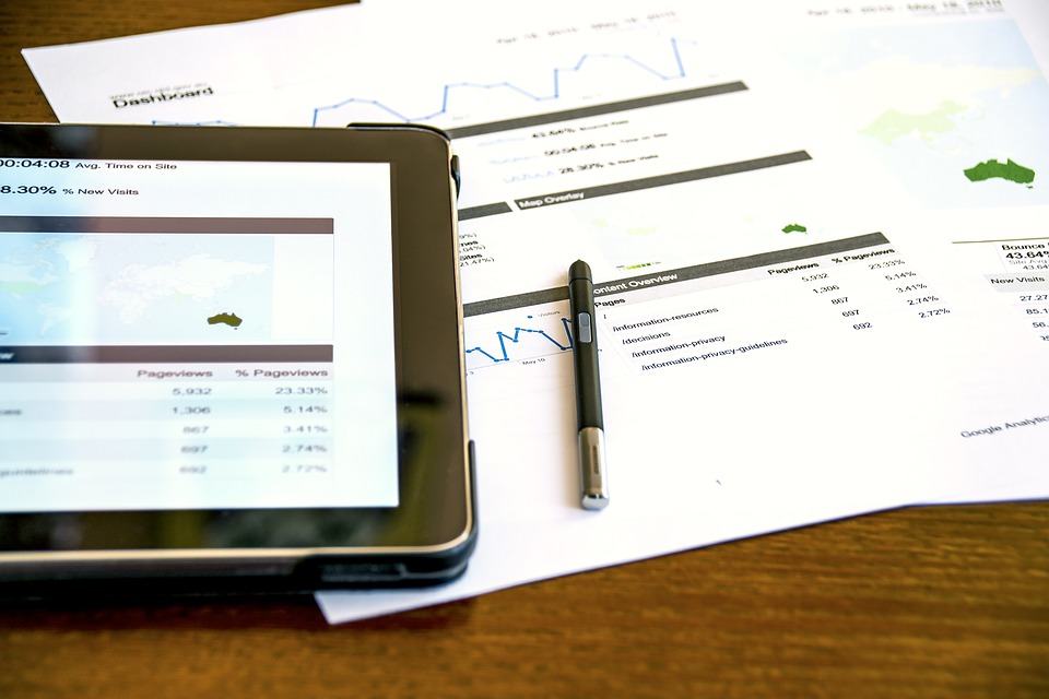 Tablet and printed Google Analytics reports on a desk showing pageviews, bounce rate, and traffic data
