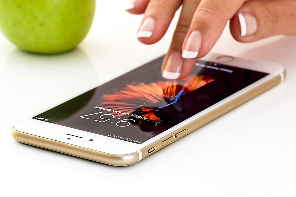 Close-up of a finger tapping an iPhone screen showing the lock screen wallpaper