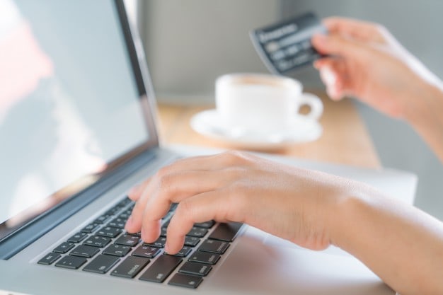 Hands typing on a laptop keyboard while holding a credit card, illustrating online shopping and conversion rate optimisation