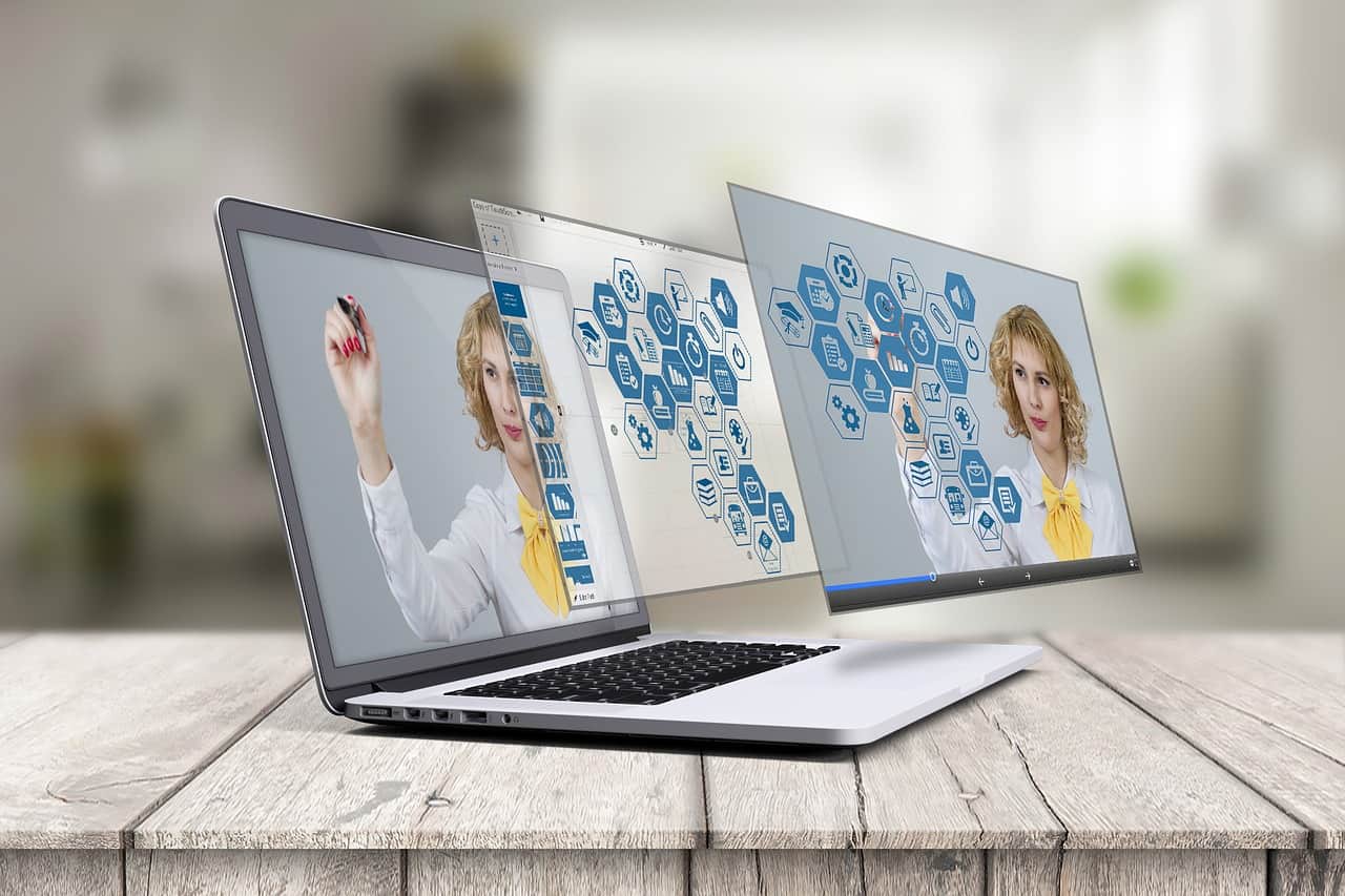 Laptop on a wooden desk displaying augmented reality digital content with hexagonal icons extending from the screen