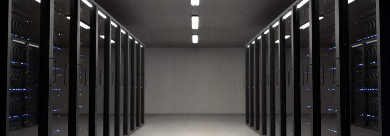 Rows of black server racks with blue LED lights in a data centre corridor, illustrating premium hosting infrastructure
