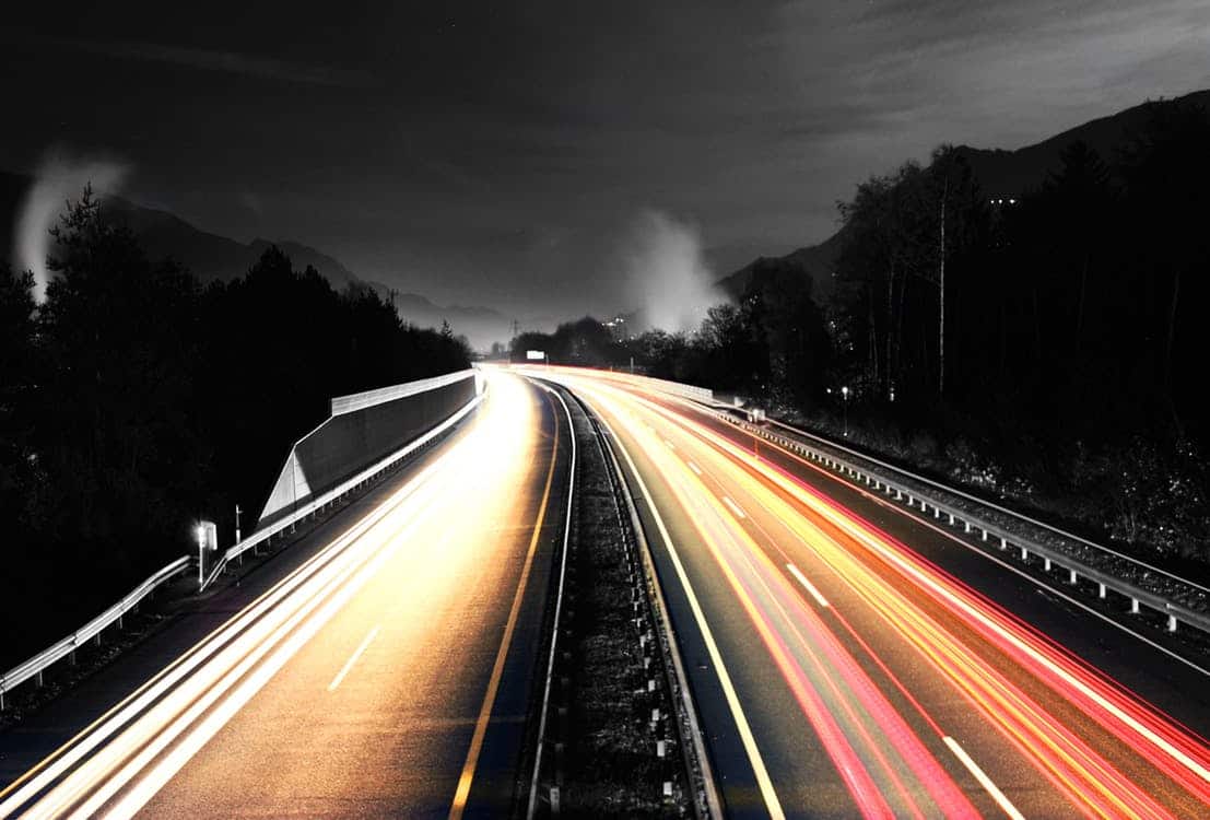 Long-exposure night highway with streaking yellow and red car light trails, representing website speed and performance