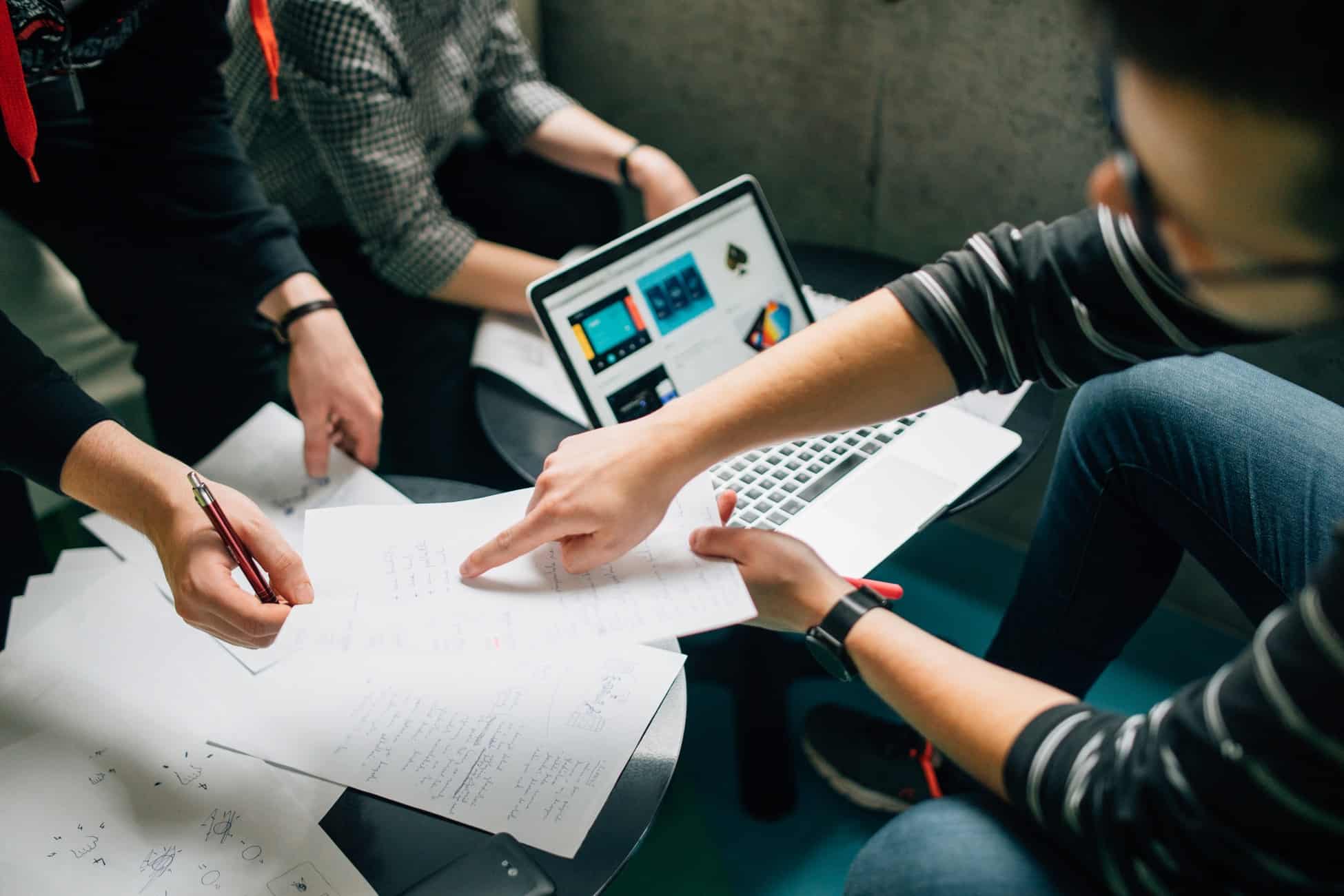 Three people collaborating over notes and laptops, reviewing a digital marketing strategy