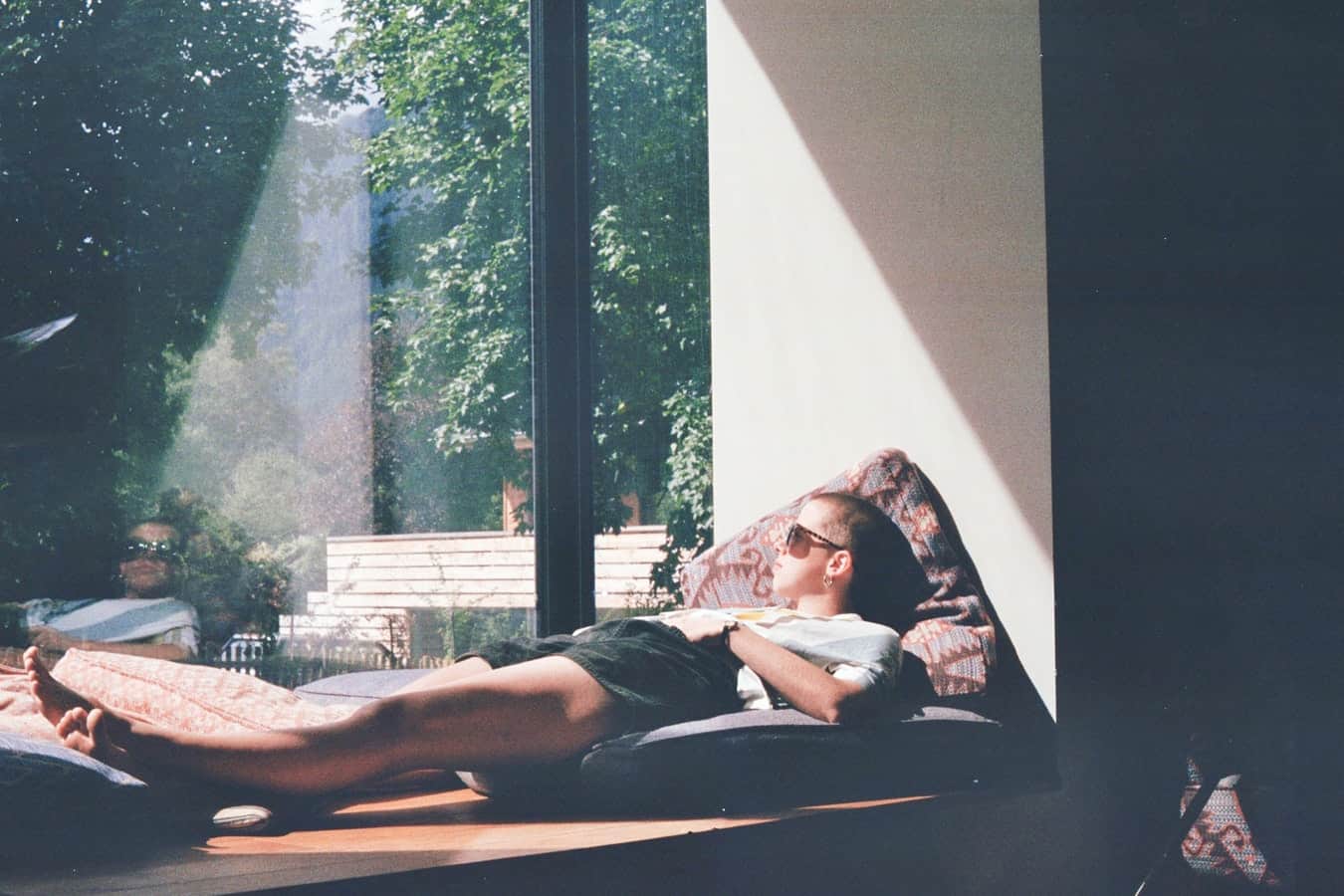 Person relaxing on a sofa by a sunlit window overlooking a garden, illustrating taking a productive break