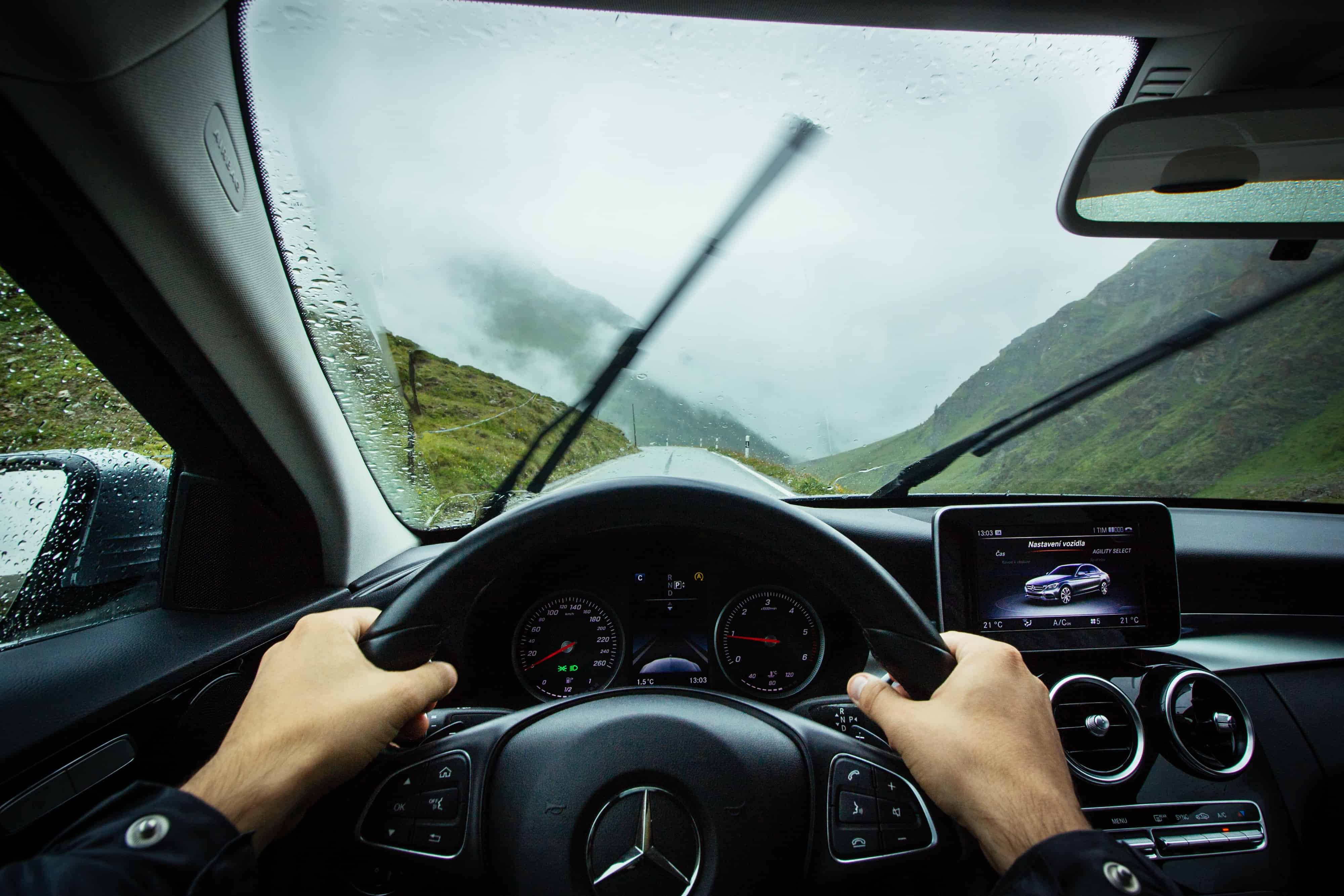Driver's-eye view inside a Mercedes on a wet mountain road, illustrating voice search navigation in 2018