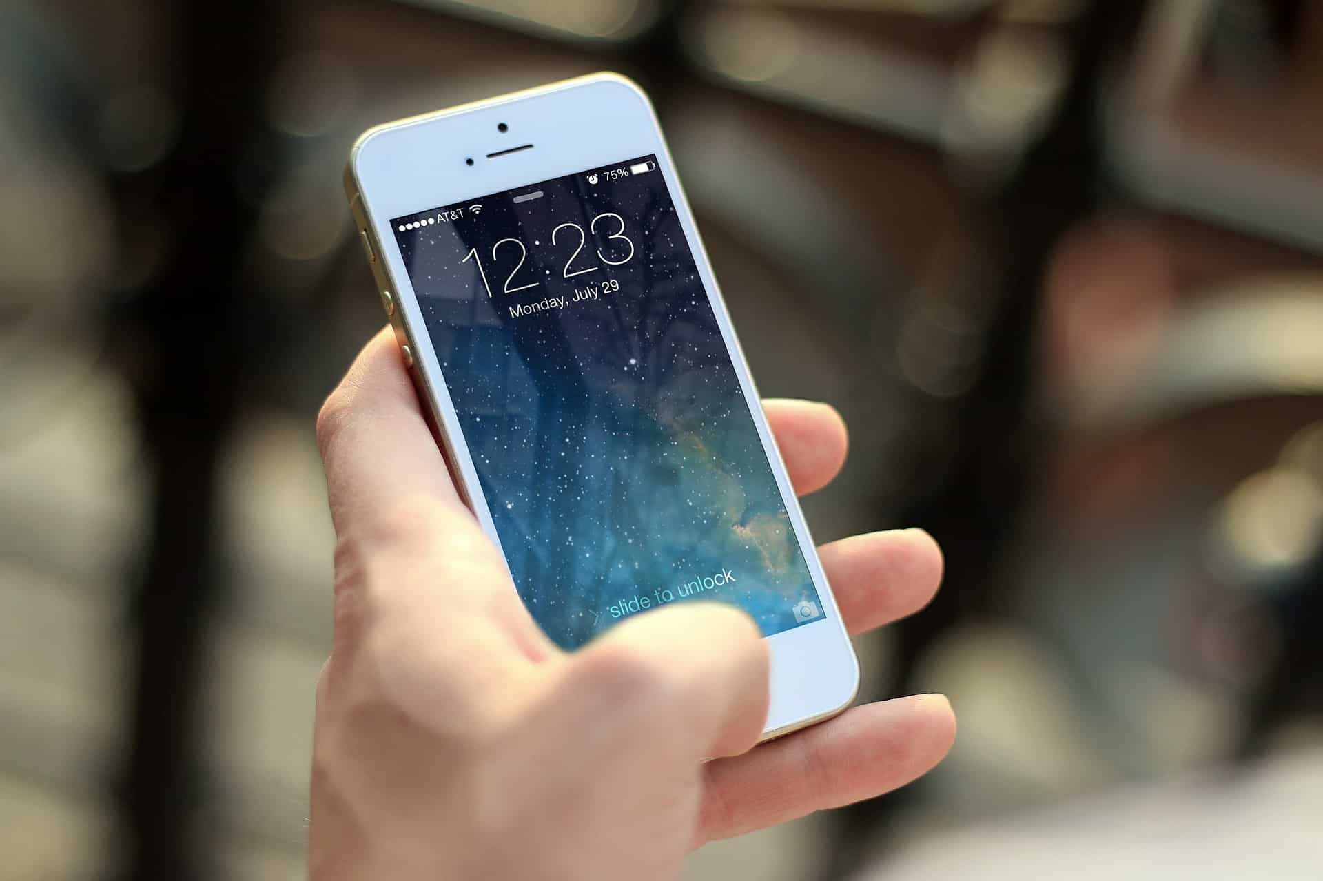 Hand holding an iPhone displaying the lock screen, illustrating mobile device usage for SEO and voice search
