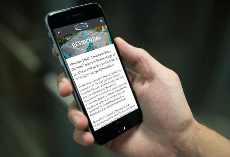 Hand holding a smartphone showing the Network Steel & Aluminium website residential page